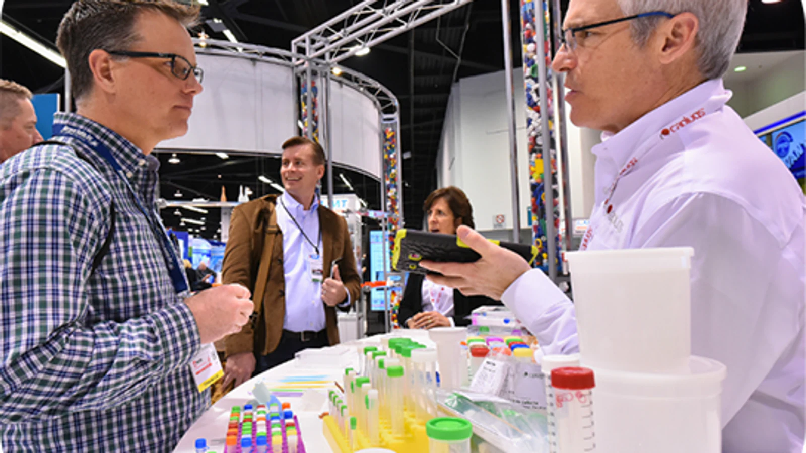 Two professionals discuss plastic sample containers at the MD&M West Plastics sector.