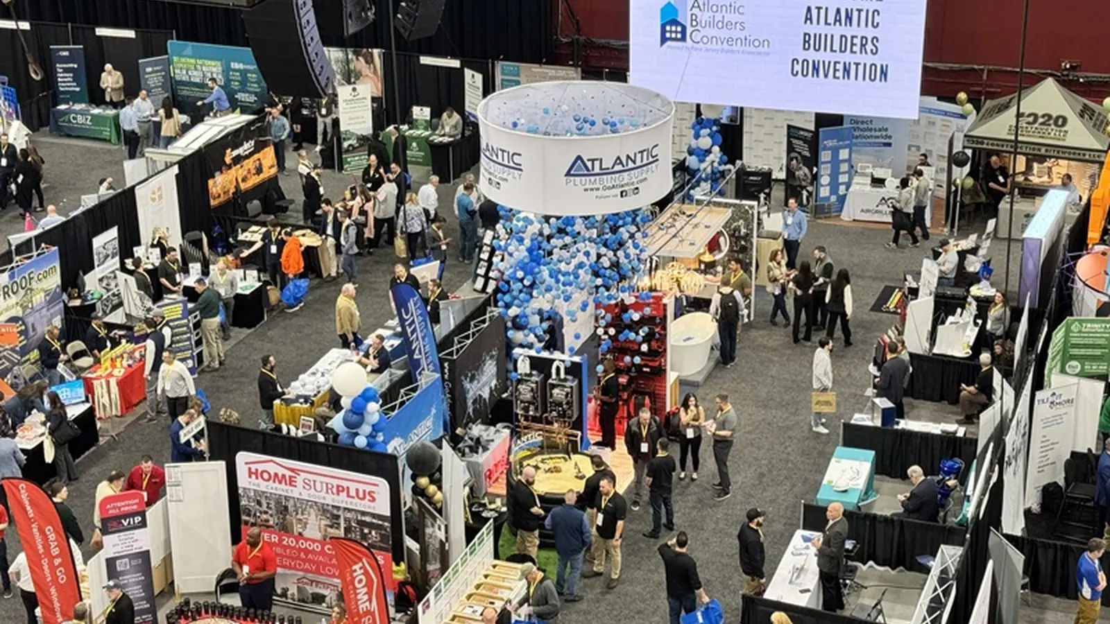 Atlantic Builders Convention attendees visit exhibitor booths beneath the event welcome banner.