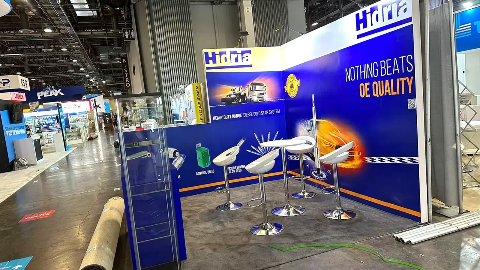 Hidria 10x10 trade show booth with a high-top conversation area and product display case.