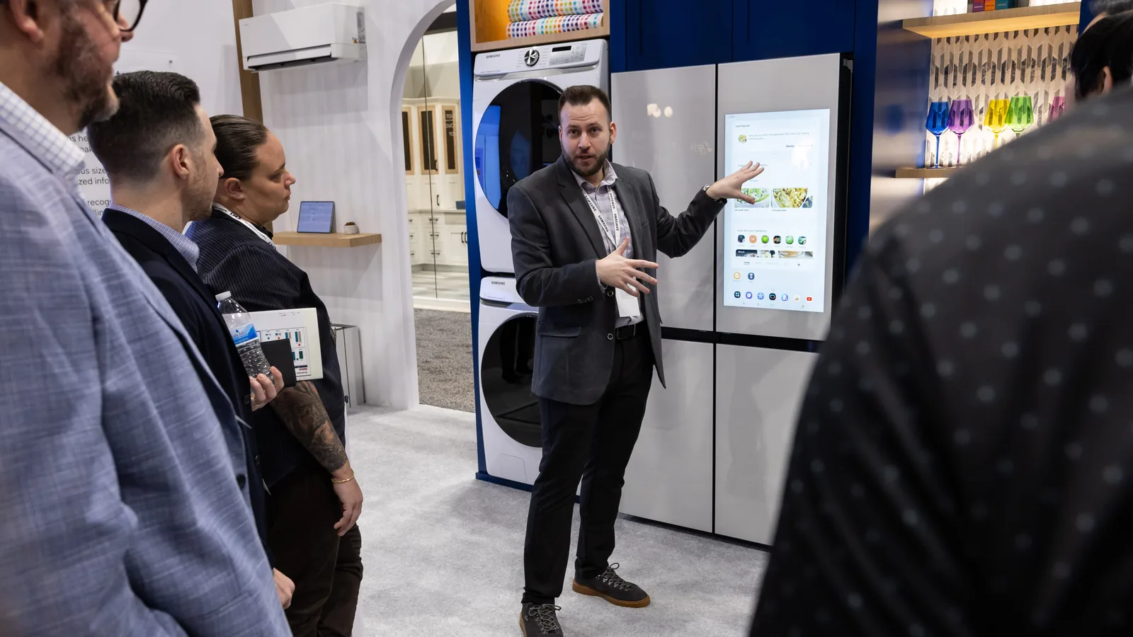 A KBIS 2026 exhibitor demonstrates a connected appliance to attendees.