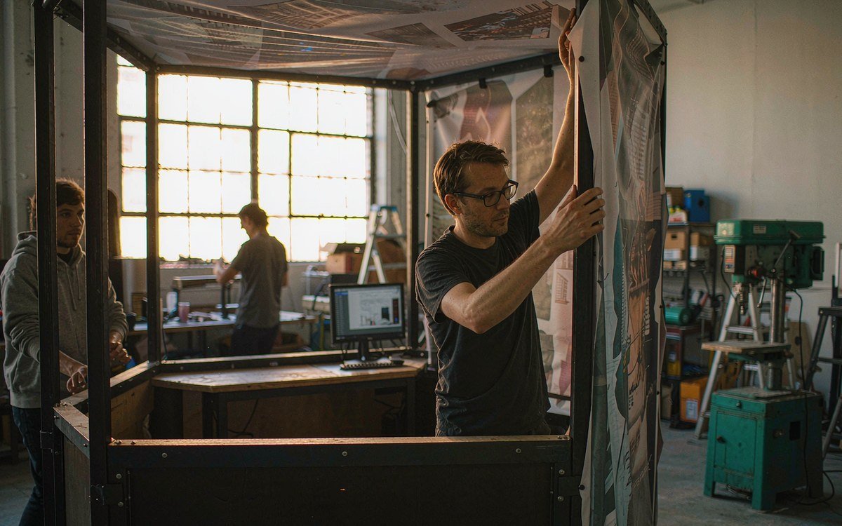 two technicians performing a trial build of a low corner booth in a fabrication hall