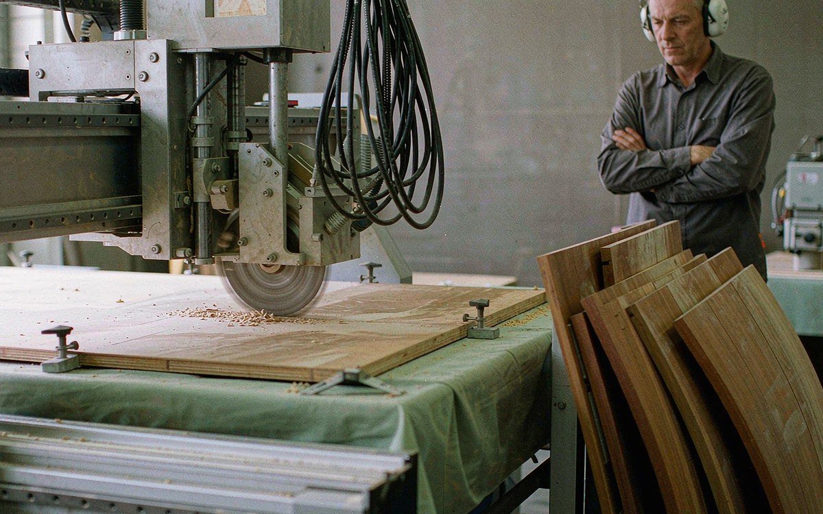CNC router cutting a sheet of board inside a fabrication workshop