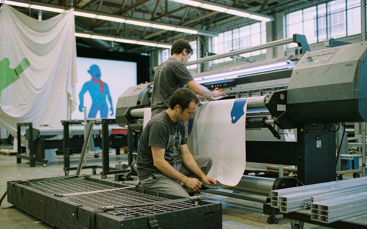 graphic production area with a printed fabric panel coming off a wide-format printer