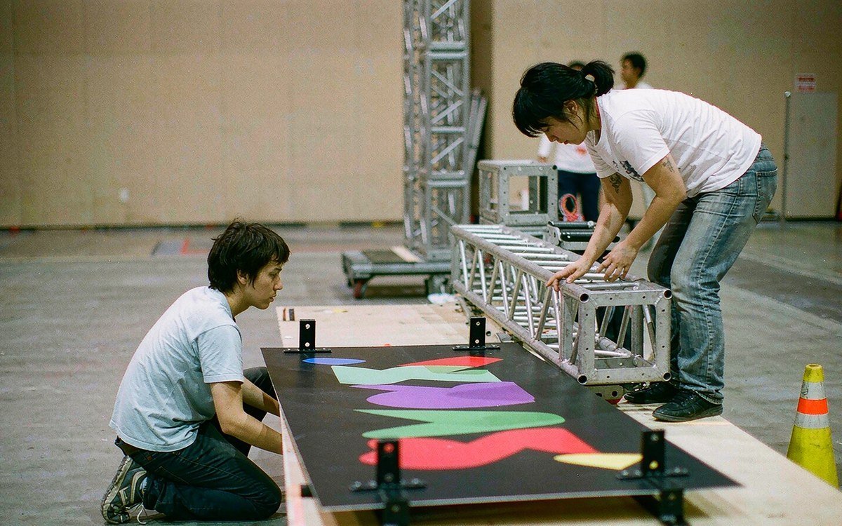 ready-to-hang printed graphic panel being inspected on a light table beside a truss frame section