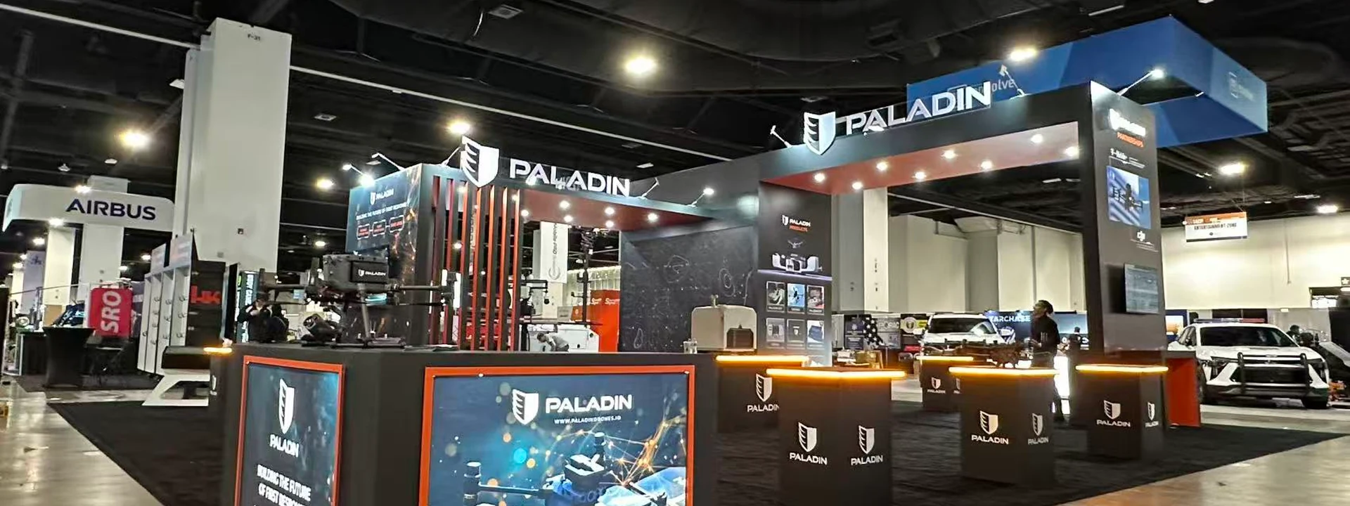 Completed Paladin island exhibit with illuminated counters, large display graphics, overhead structures, and open meeting space.