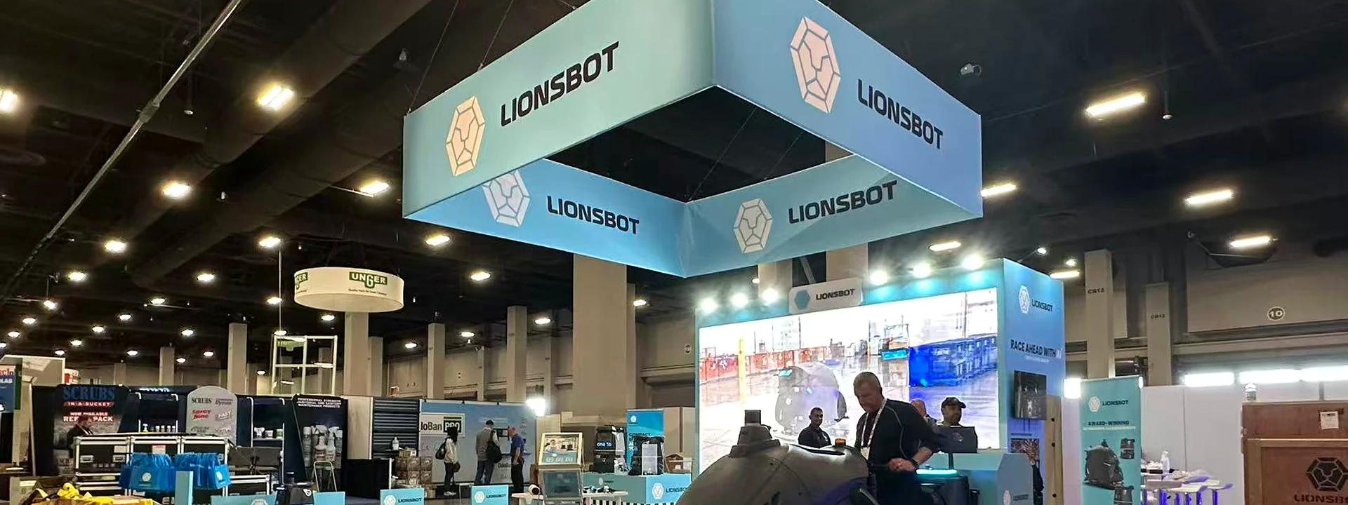 LionsBot robotics booth with blue counters, overhead branding, and cleaning robots