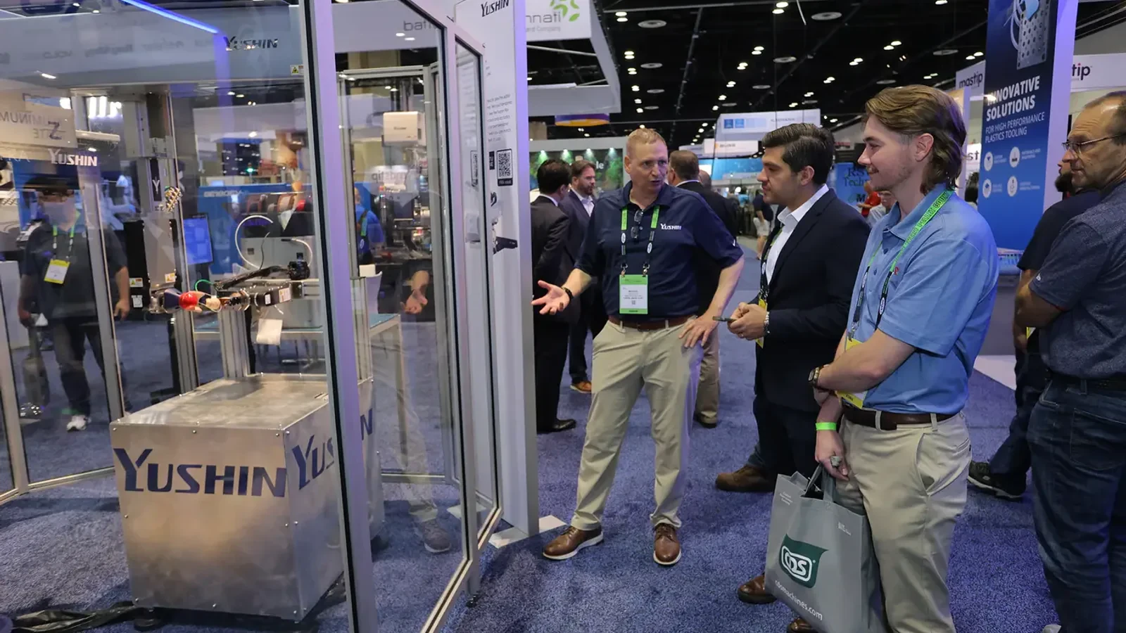 Visitors watch a plastics automation demonstration on the NPE show floor.