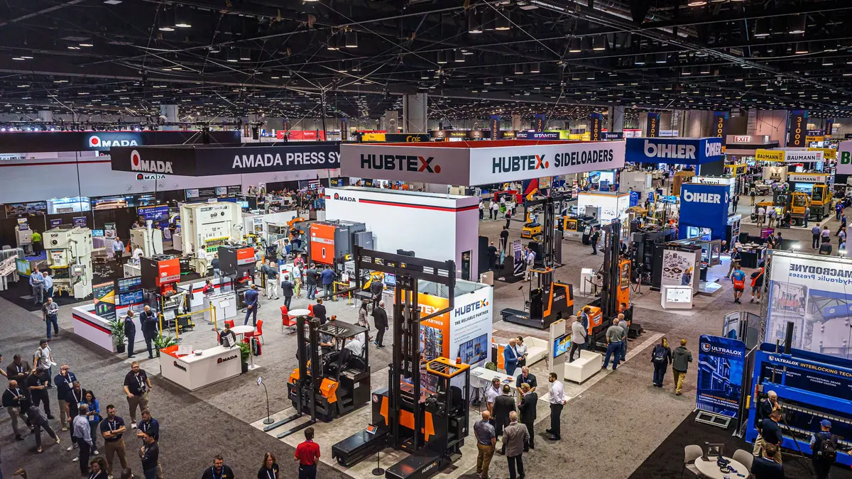 Wide view of machinery exhibits and attendees on a previous FABTECH show floor.