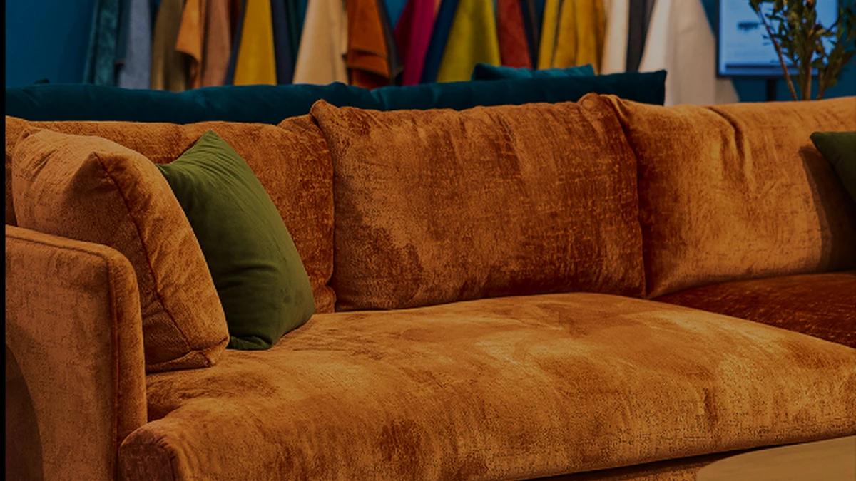 A brown upholstered sofa featured in official Spring 2026 High Point Market campaign artwork.