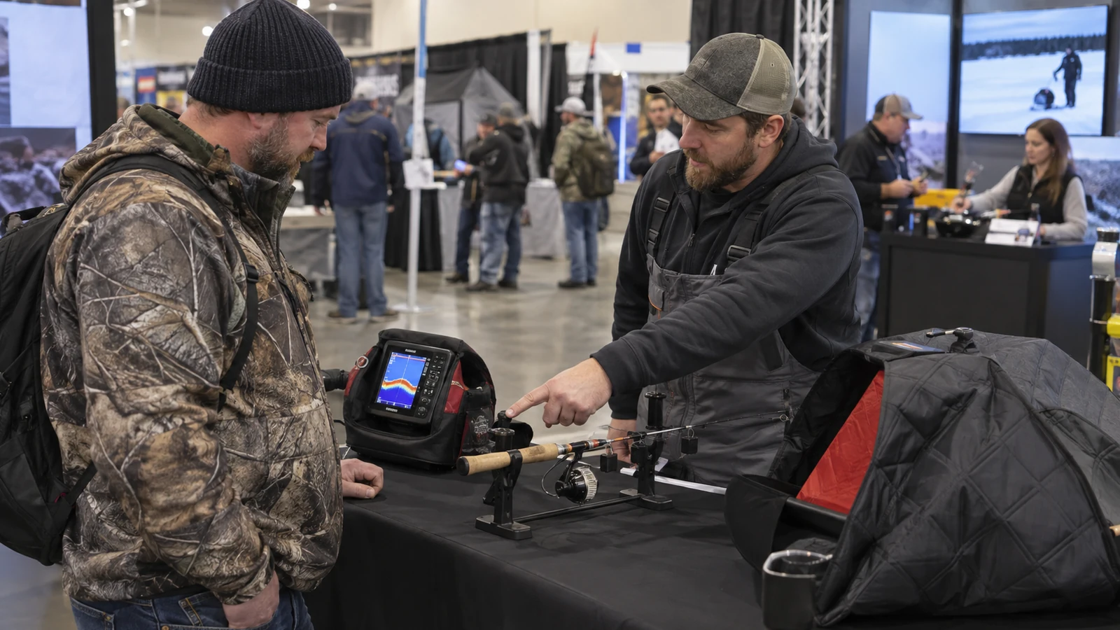 Angler comparing ice-fishing electronics and accessories with a booth specialist
