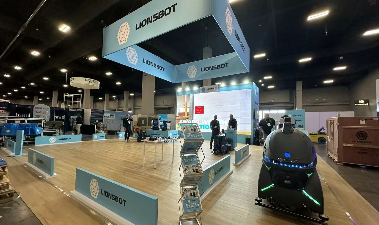 LionsBot cleaning robot positioned at an ISSA booth for an operator workflow discussion