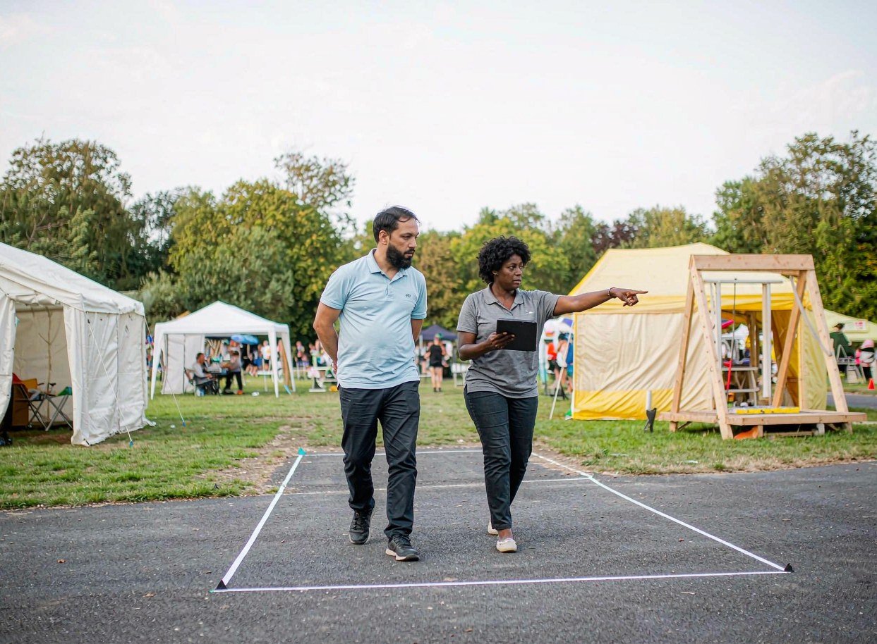 Site review of a marked outdoor exhibit space beside grass and pavement before building a booth