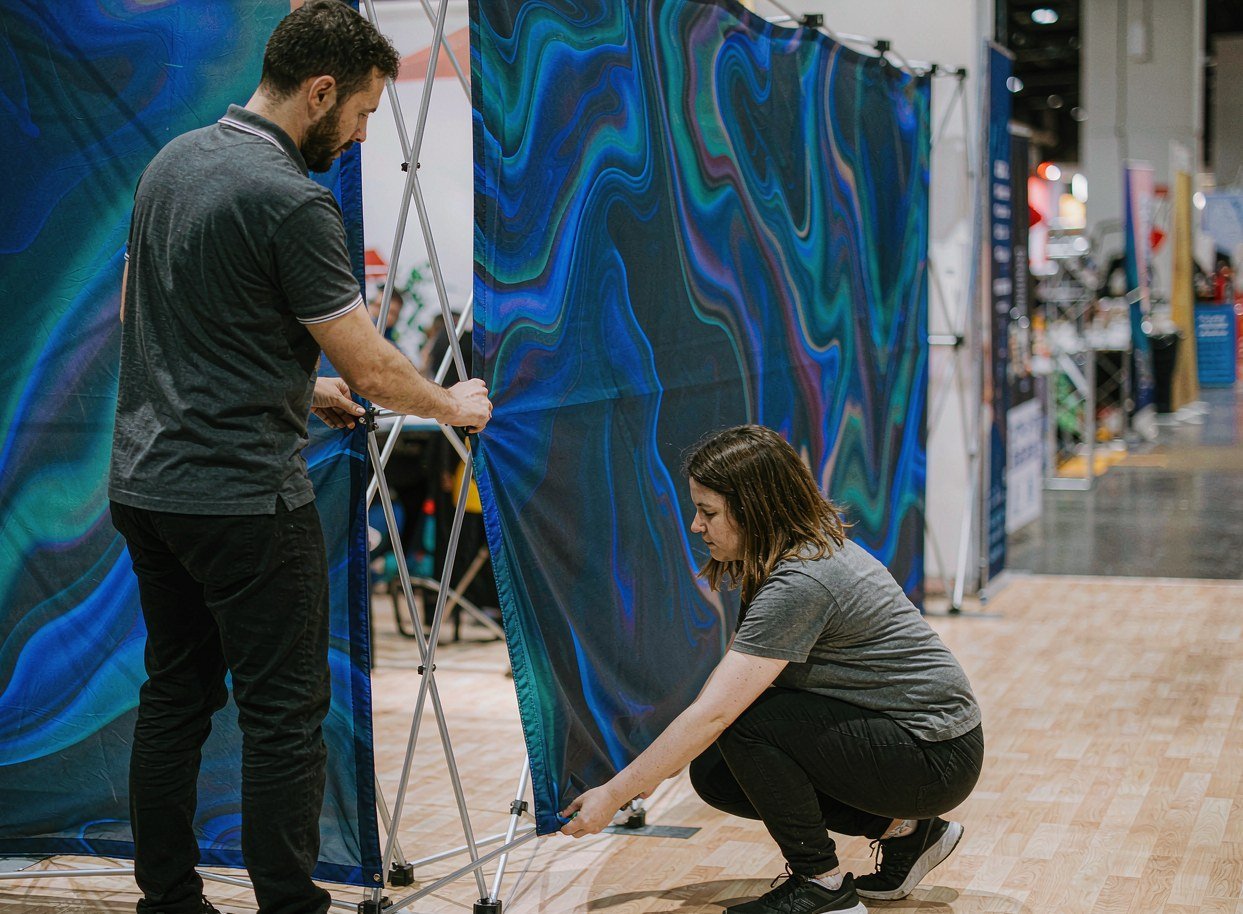 Pop-up trade show display being opened with a single attached tension fabric graphic