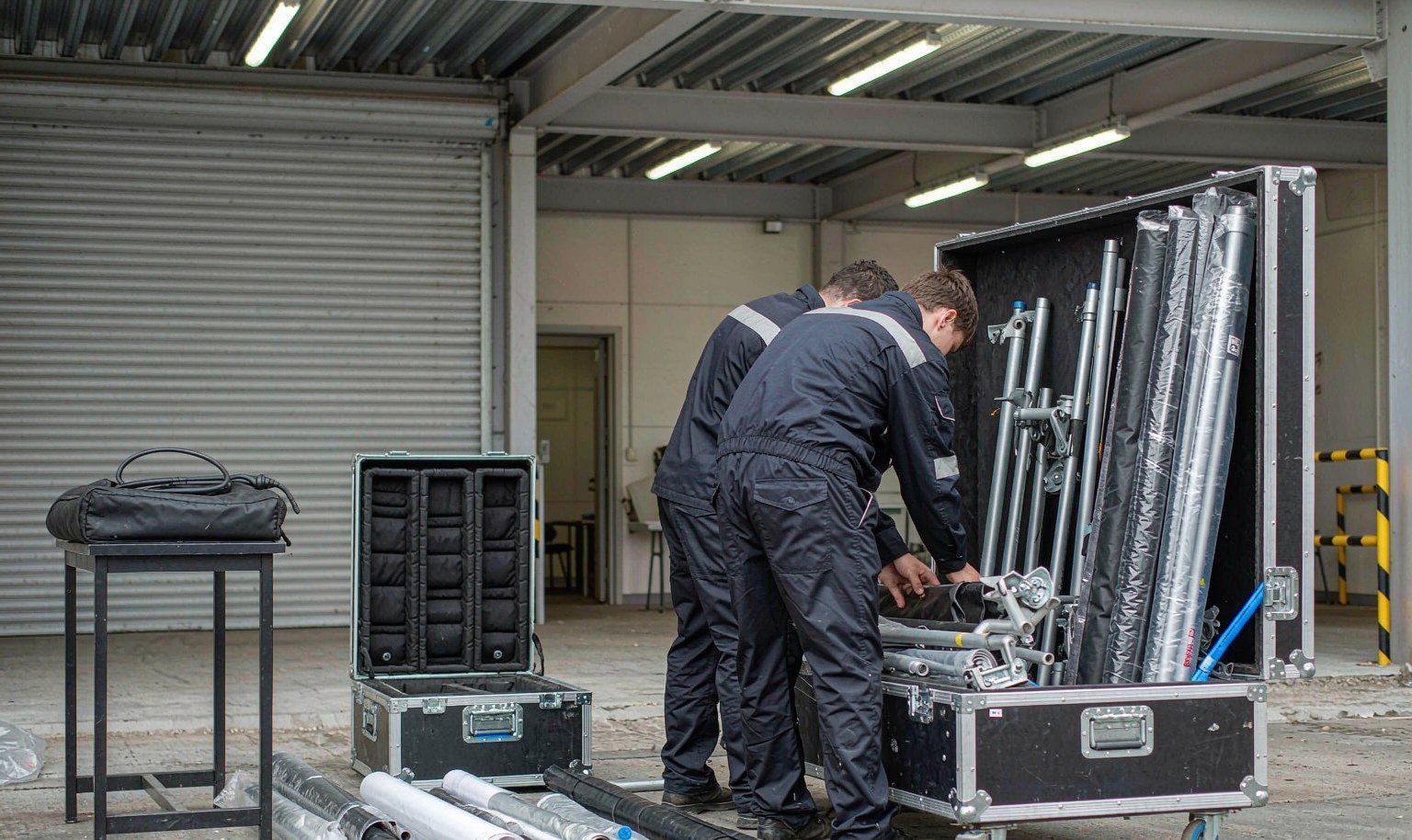 Crew packs a disassembled portable rental booth into flight cases before shipping to the venue