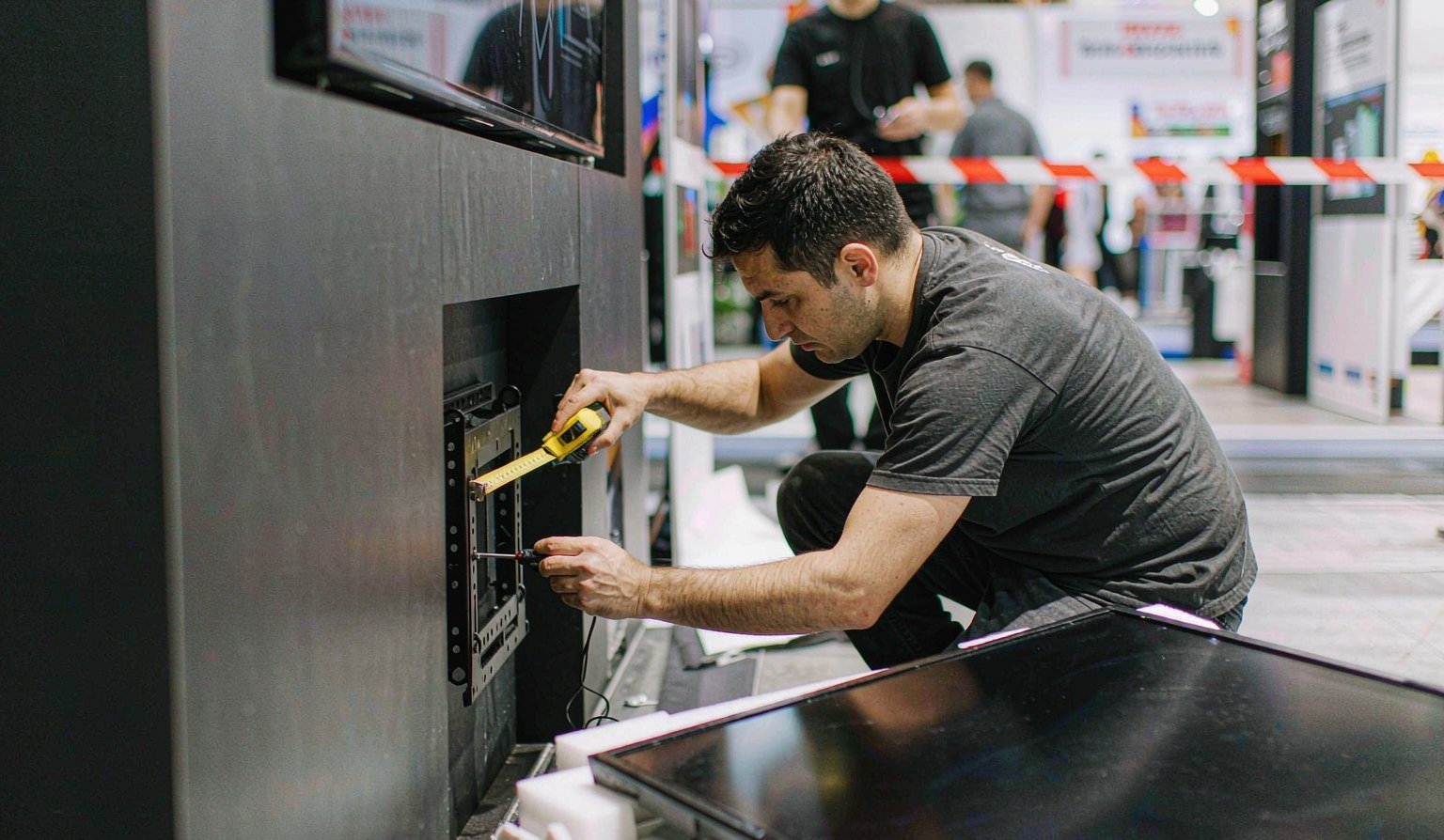 Flat display mounting bracket being fitted into a booth wall panel in the workshop - Trade Show AV Rental