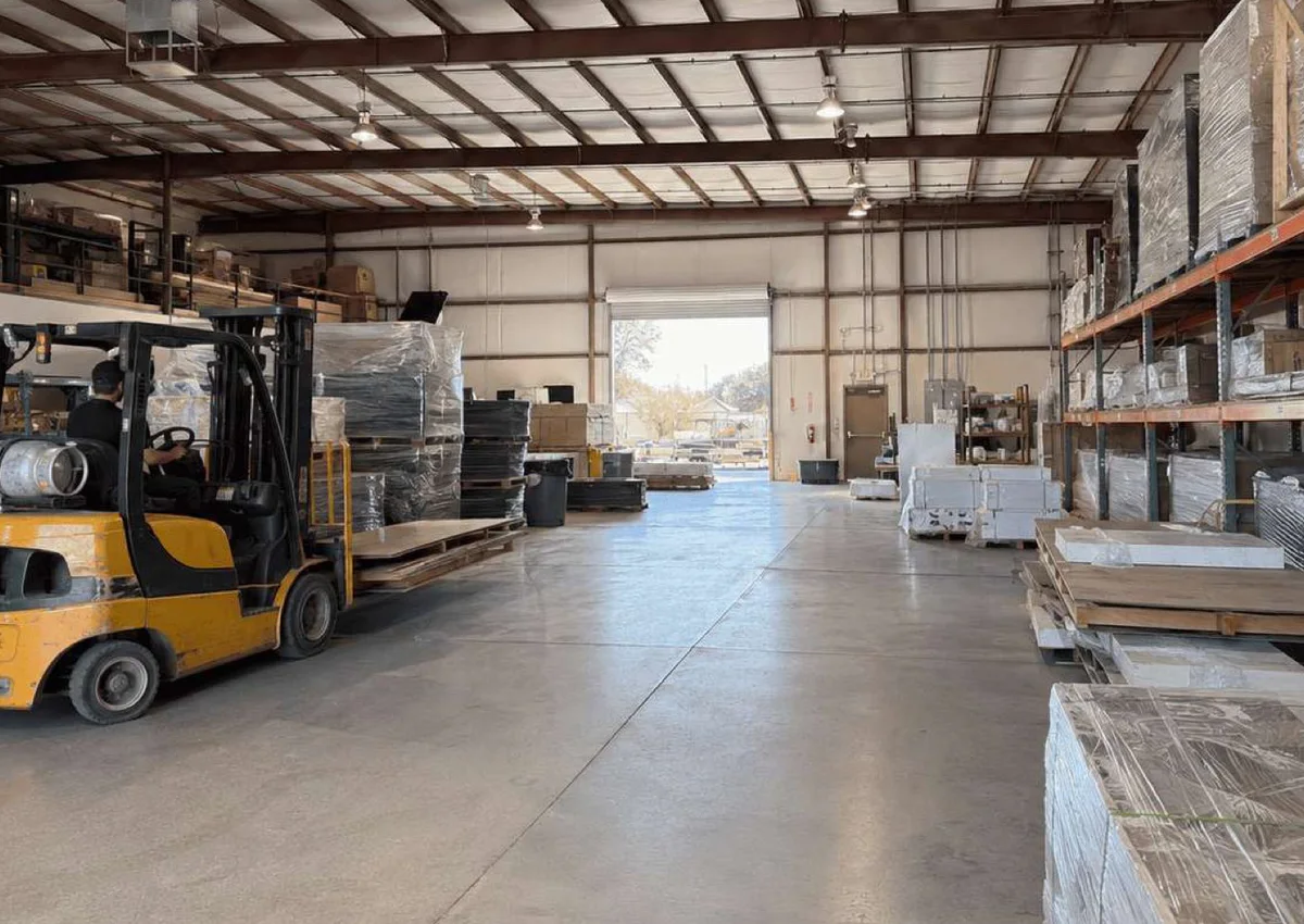 Forklift beside wrapped exhibit components in a warehouse staging area