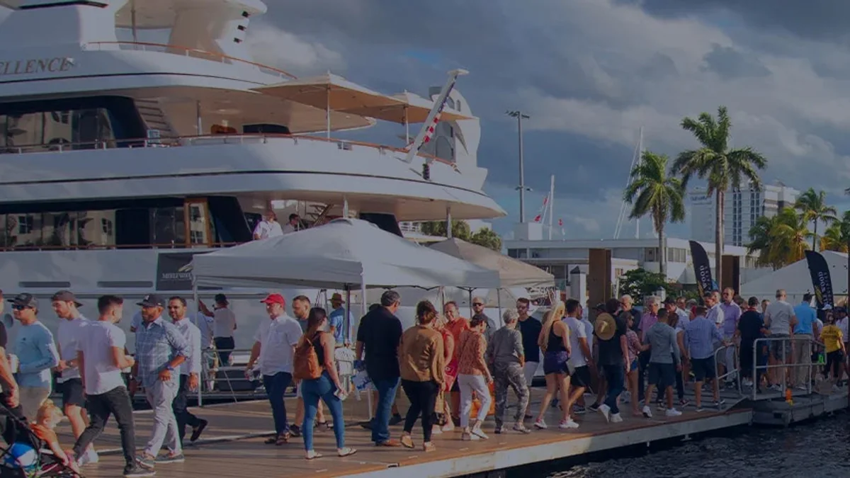 Visitors walking beside yachts at the Discover Boating Miami International Boat Show
