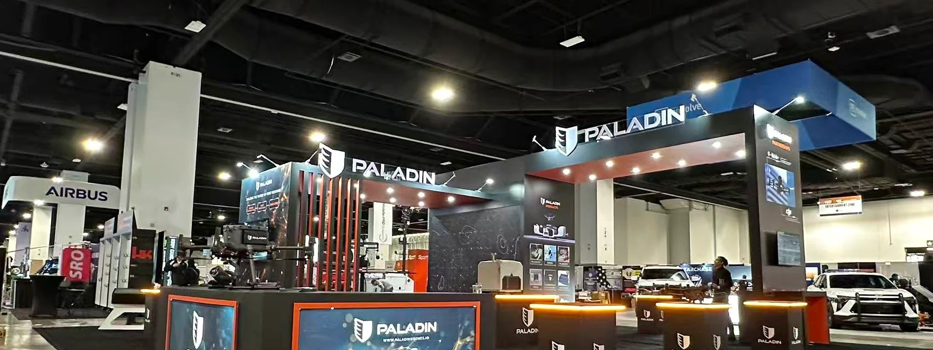 Paladin Drones exhibit with black counters, orange accents, and large video displays