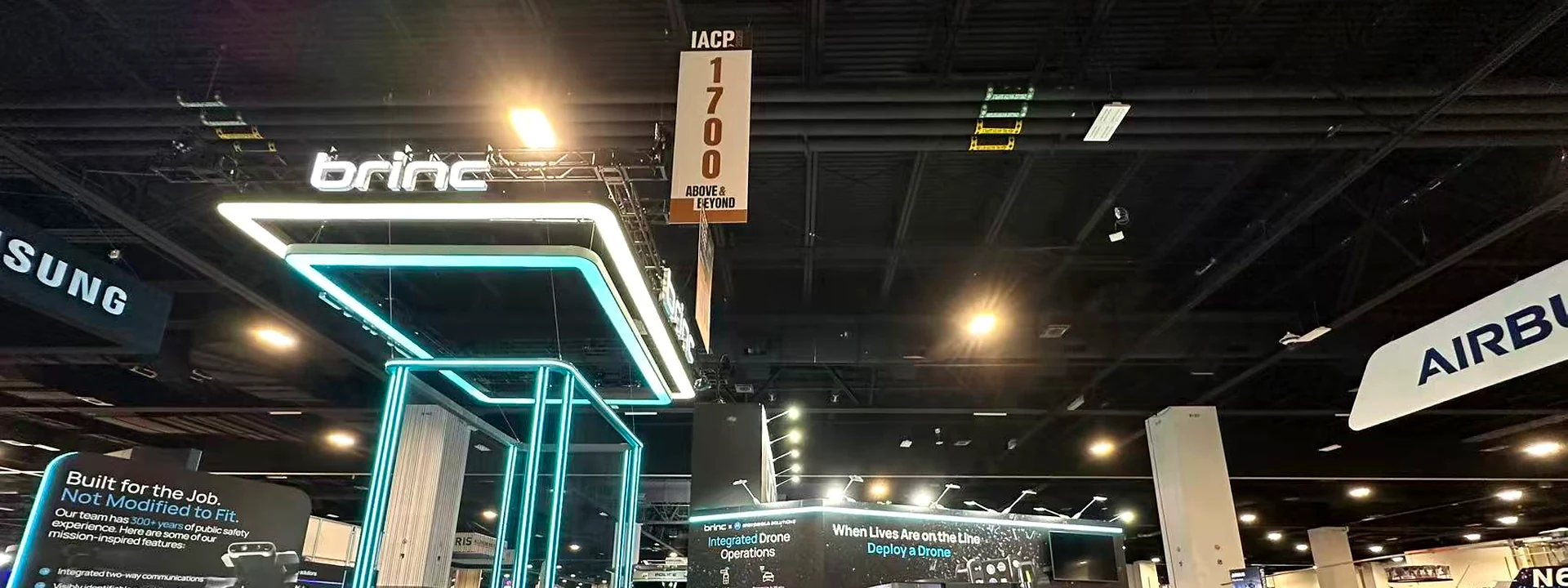 Brinc technology booth with cyan illuminated structures and interactive display stations