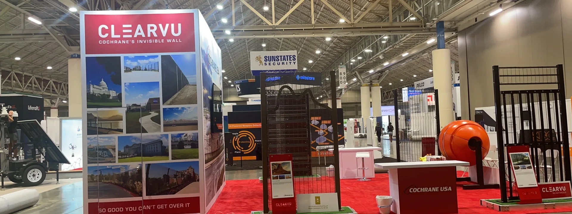 Red and black trade show booth with product displays, illuminated panels, and an open presentation area.
