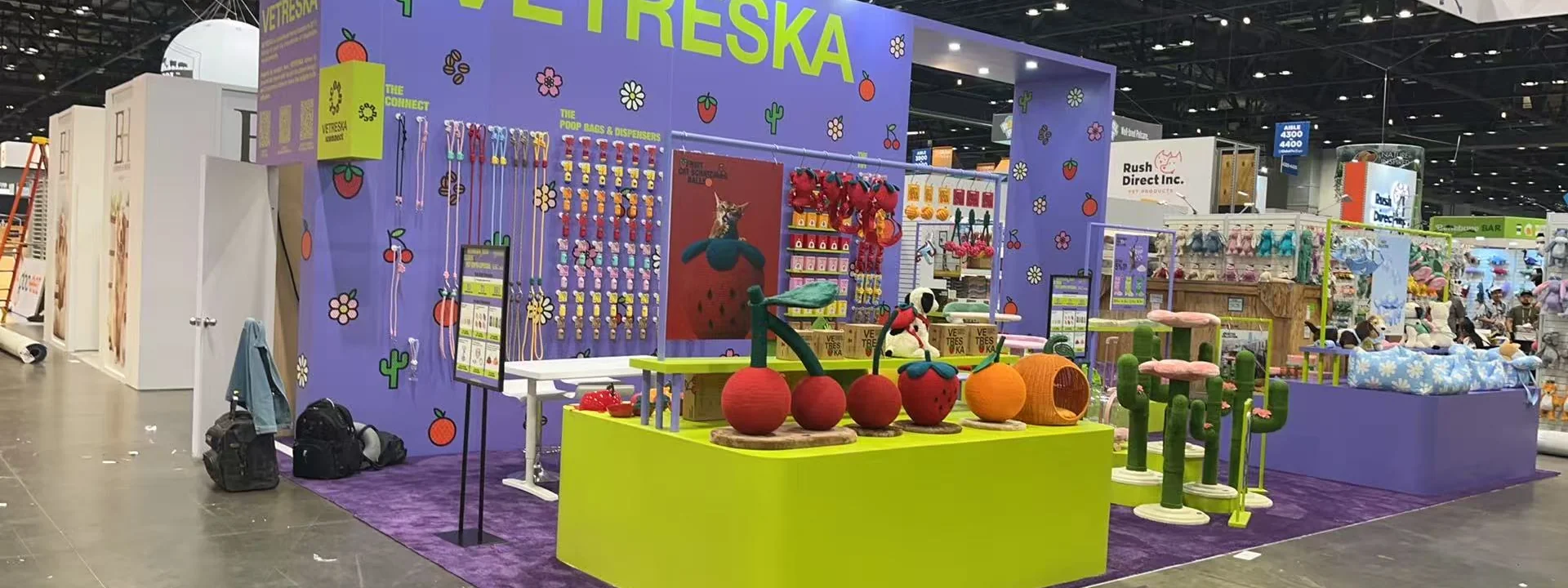 Colorful trade show booth with illuminated product walls, display tables, and freestanding counters.