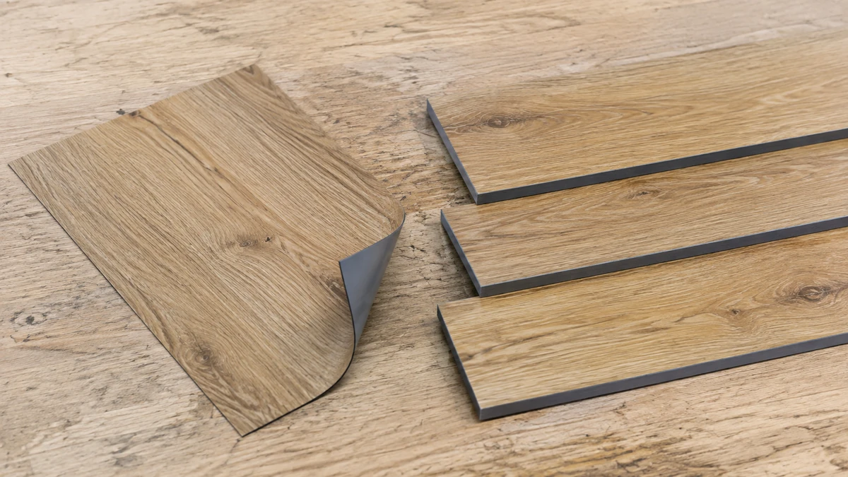 Illustrative comparison of a curled wood-look vinyl sheet and three flat rigid flooring plank samples.